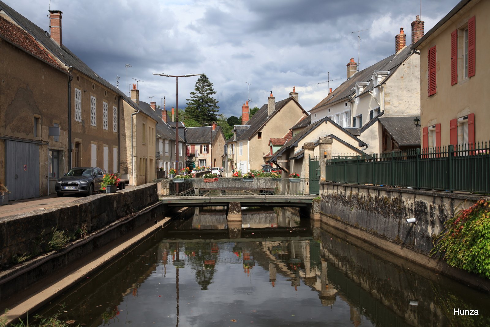 Centre-ville de Moulins-Engilbert avec des maisons anciennes, un petit canal et des passerelles.