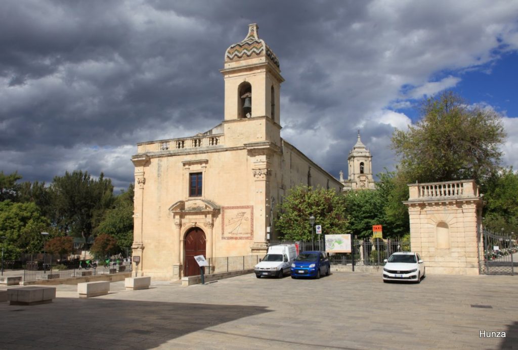 Chiesa di San Vincenzo Ferreri à l'entrée du jardin Ibleo à Ragusa Ibla, avec le clocher de l'église San Giacomo Apostolo en arrière-plan sous un ciel d'orage.