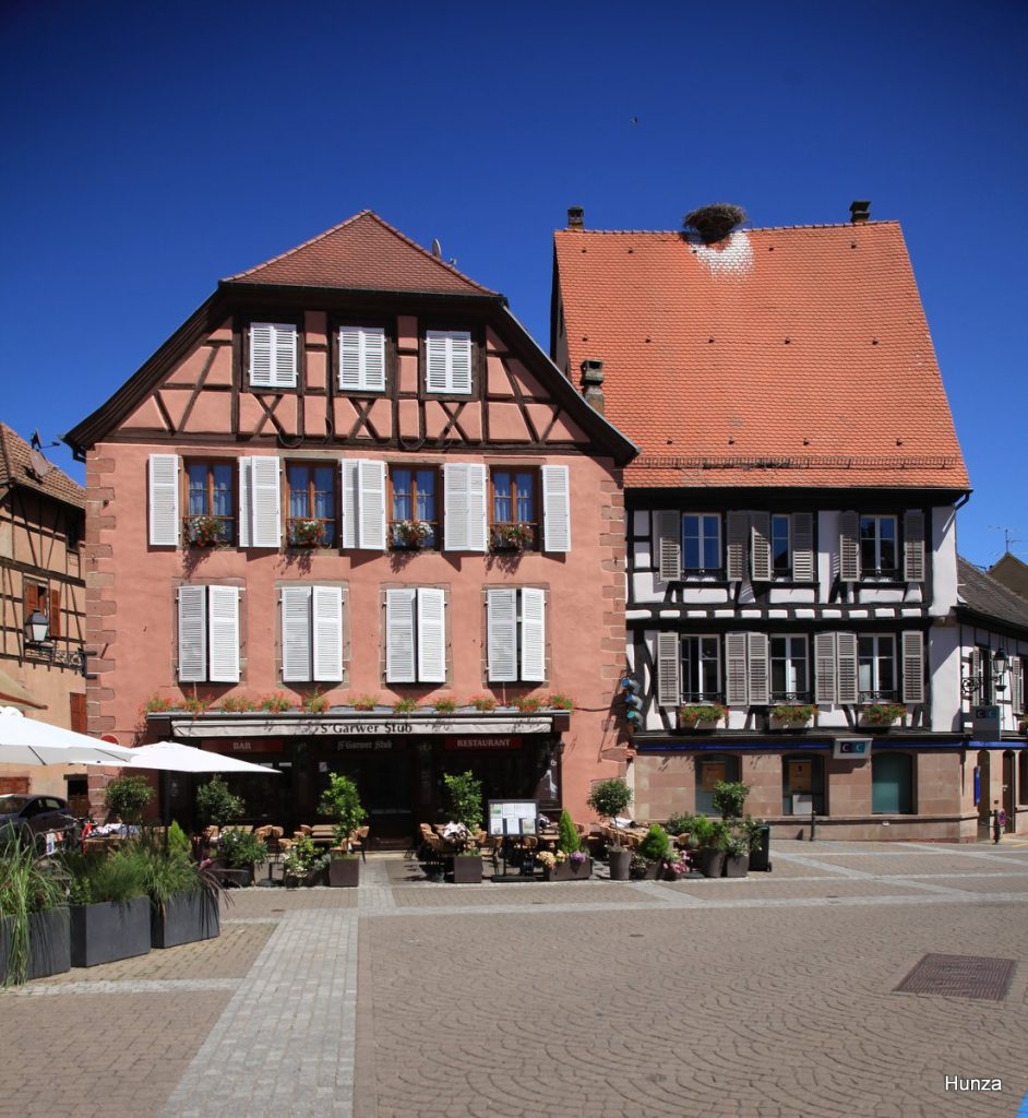 Maisons à colombages de la place de la 1ʳᵉ Armée dont l'une est surmontée d'un nid de cigognes à Ribeauvillé
