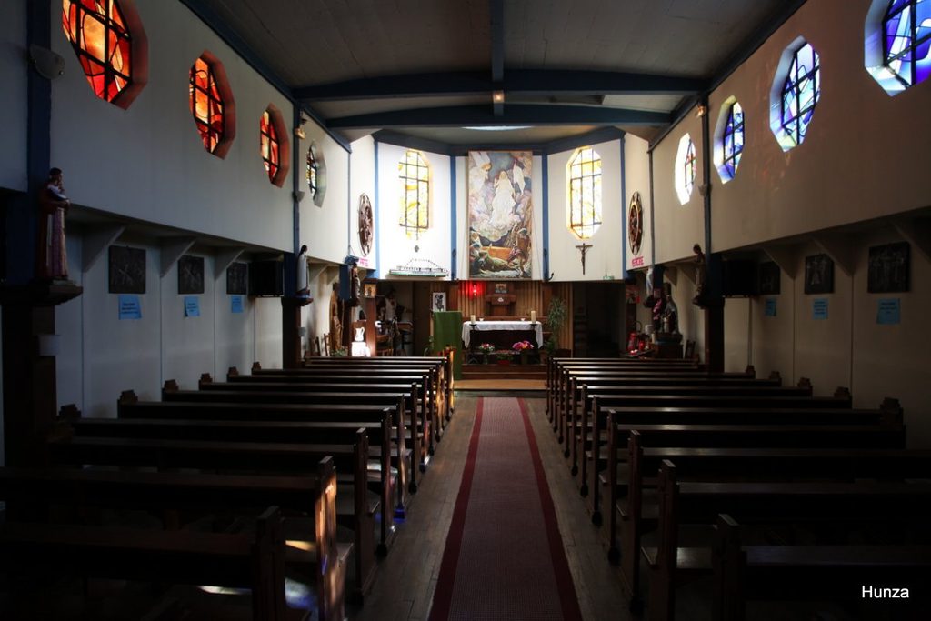 Intérieur de la chapelle « Je Sers » à Conflans-Sainte-Honorine, avec ses vitraux colorés et son autel.