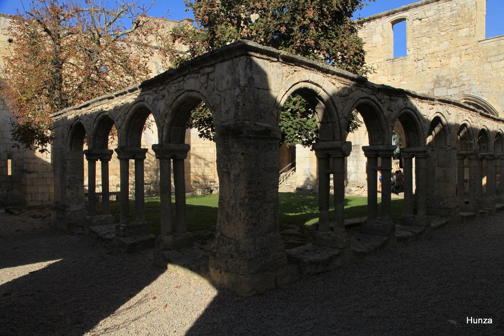 Arcades en pierre et jardin du cloître des Cordeliers à Saint-Émilion